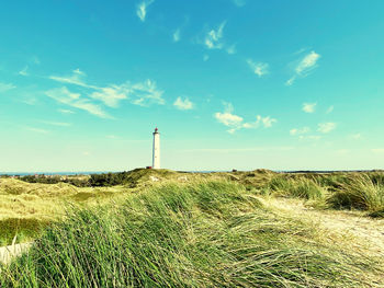 Lighthouse on field against sky