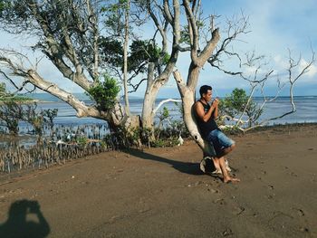 Full length of young man at beach against sky