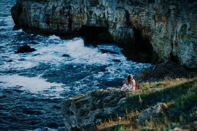 People sitting on rock by sea
