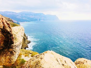 Scenic view of sea and mountains against sky
