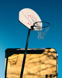 Low angle view of basketball hoop against clear blue sky