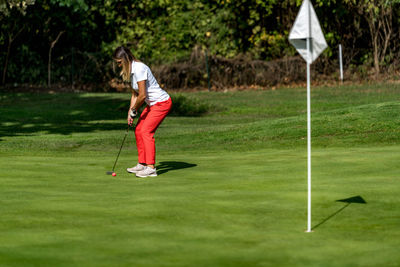 A woman and a man playing golf, woman putting