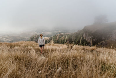 Girl walking through tall grass on a foggy morning in new zealand