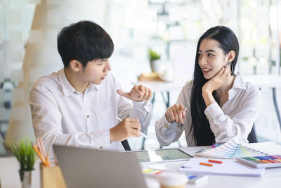 Young colleagues discussing at desk in office