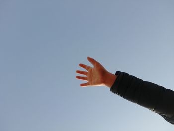 Cropped hand of person against clear sky