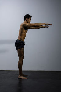 Shirtless muscular man exercising against wall