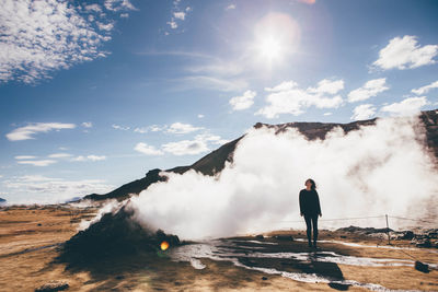 Woman standing on against sky during sunny day