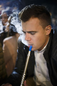 Young man smoking hookah at night