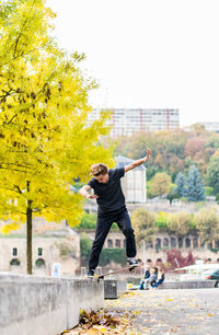 Full length rear view of man skateboarding on tree