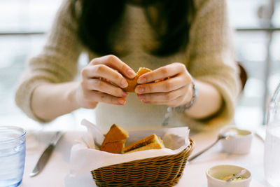 Midsection of woman holding fortune cookie over basket