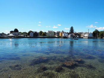 Buildings by sea against blue sky