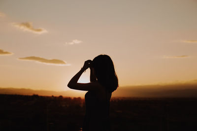 Mature woman standing on terrace against sky during sunset