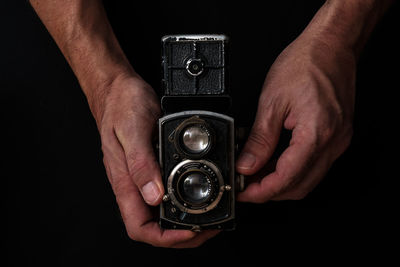 Close-up of hand holding camera against black background