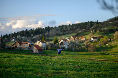 Houses on field by buildings against sky