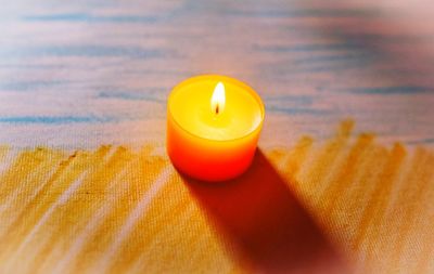 Close-up of illuminated candle on table
