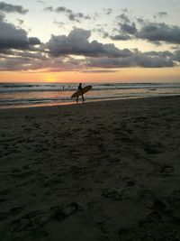 Silhouette man on beach against sky during sunset