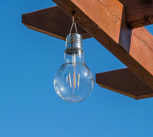 Low angle view of light bulb against clear blue sky