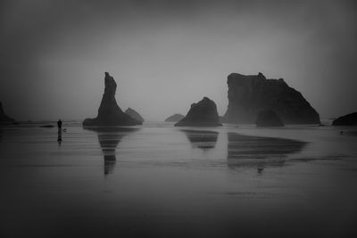 Reflection of rocks in sea against sky