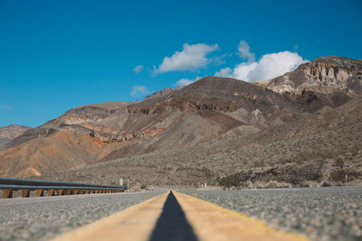 Road by mountains against sky