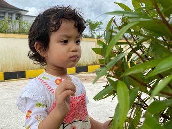 Cute girl looking away while standing against plants