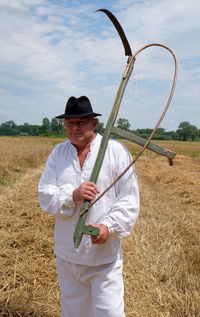 Man holding umbrella while standing on field against sky