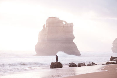 Rock formation on beach against sky