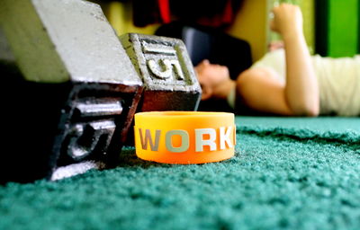 Text on wristband with dumbbells by woman exercising at home
