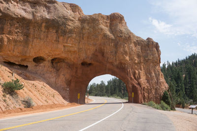 Road leading towards rock formation against sky