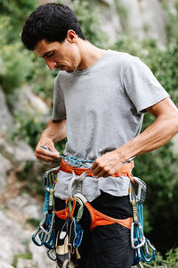 Male hiker with harness tying rope on waist while preparing form rappelling