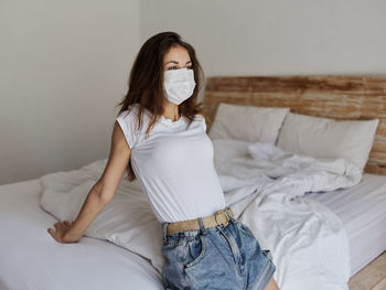 Young woman sitting on bed at home