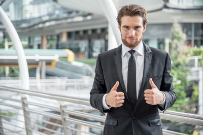 Portrait of confident businessman standing in elevated walkway in city