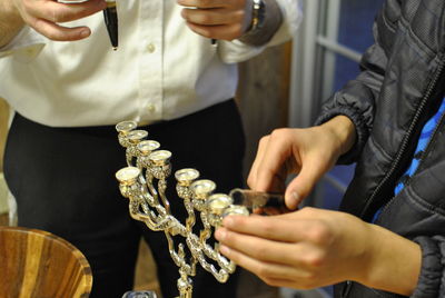 Midsection of person putting candle in menorah