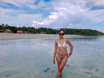 Portrait of woman standing in sea against sky