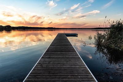 Pier over lake against sky during sunset