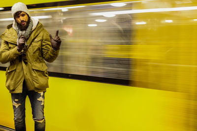 Man gesturing against blur metro at subway station