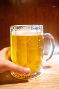 Close-up of hand holding beer glass on table