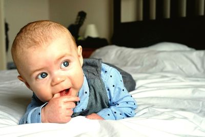 Cute baby boy lying down on bed at home