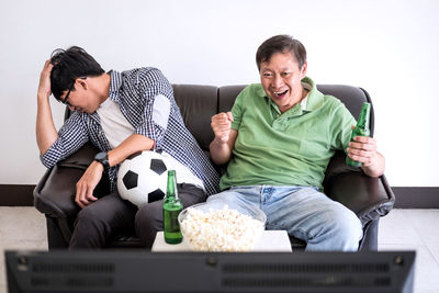 Family with food and drink watching sports on tv at home