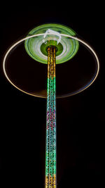 Low angle view of illuminated ferris wheel against black background