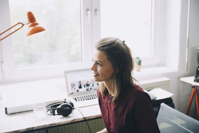 Confident businesswoman looking away while sitting at desk in office