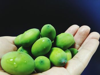 Close-up of hand holding fruit over black background
