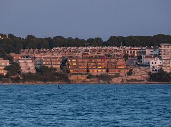 Buildings by sea against clear sky