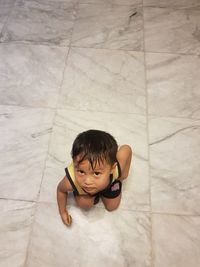 High angle view of cute baby boy on tiled floor