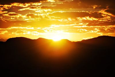 Scenic view of silhouette mountains against romantic sky at sunset
