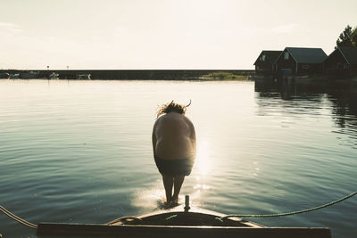 Rear view of shirtless man diving in lake from boat on sunny day