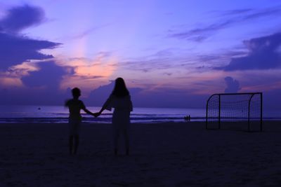 People on beach against sky during sunset