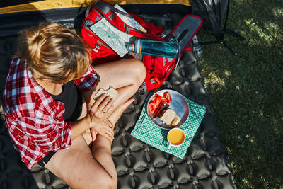 Woman having breakfast sitting by tent at camping. spending vacations close to nature. camp life