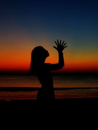 Silhouette woman standing by sea against sky during sunset