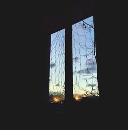 Silhouette buildings seen through window during sunset