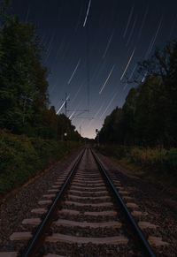 Railroad tracks against sky at night